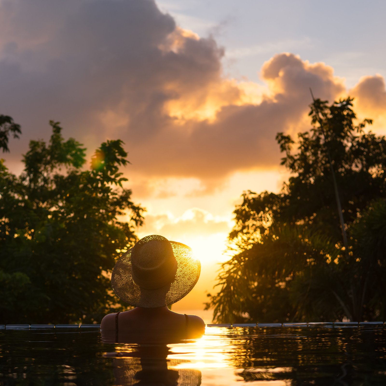Girl in the pool on a sunset background.